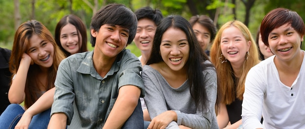 Group of young Asian friends hanging out and relaxing together at the park outdoors