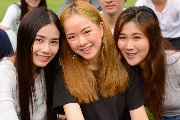 Group of young Asian friends hanging out and relaxing together at the park outdoors