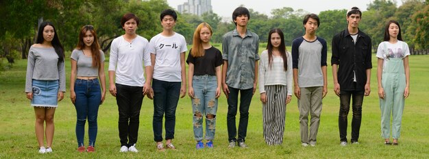 Group of young Asian friends hanging out and relaxing together at the park outdoors