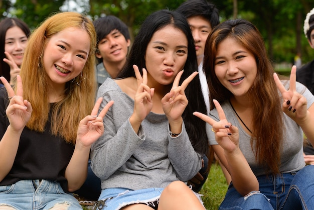 屋外の公園で一緒にぶらぶらしてリラックスしている若いアジアの友人のグループ