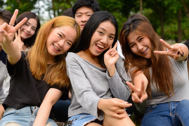 Group of young Asian friends hanging out and relaxing together at the park outdoors