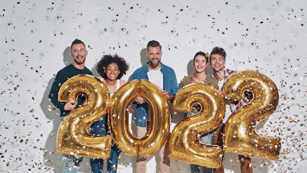 Group of young beautiful people in casual clothing carrying gold colored numbers and smiling