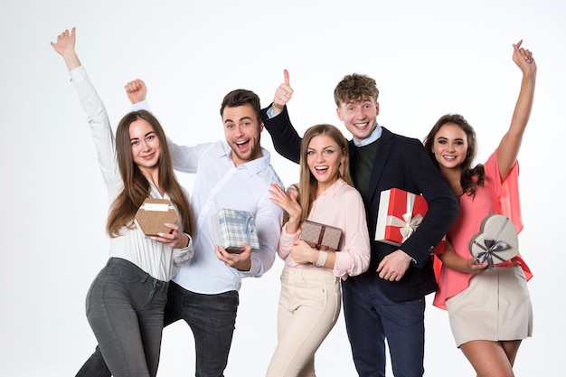 Group of young beautiful people with presents rejoice over a white background.