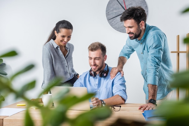 Group of young business colleagues working with laptop in office together