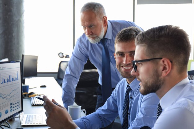 Group of young business men in formalwear working using computers while sitting in the office.