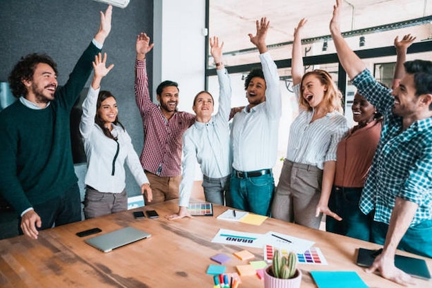 group of young business people celebrating their success multiethnic group of creative people on a business meeting in modern office cheerful creative team raising their hands together in the air