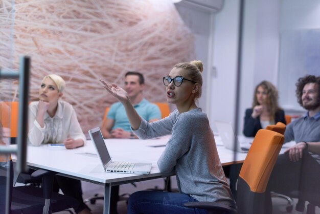 Group of a young business people discussing business plan at modern startup late night office building