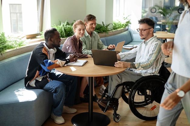 Group of young business people discussing online presentation on laptop during teamwork in office