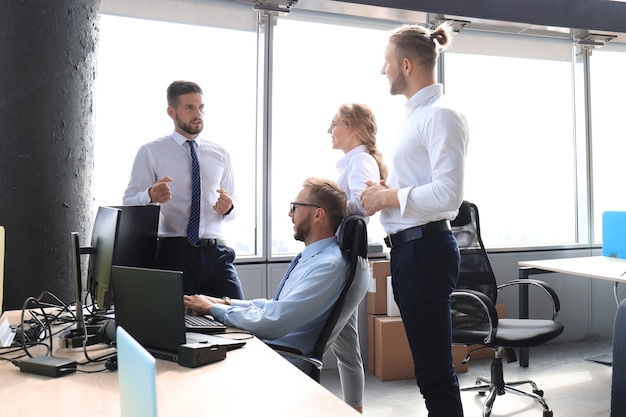 Foto gruppo di giovani uomini d'affari che discutono di qualcosa mentre lavorano nell'ufficio creativo.