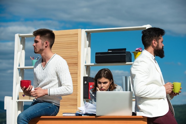 Group of young business people on office terrace outdoor talking and drinking tea or coffe together