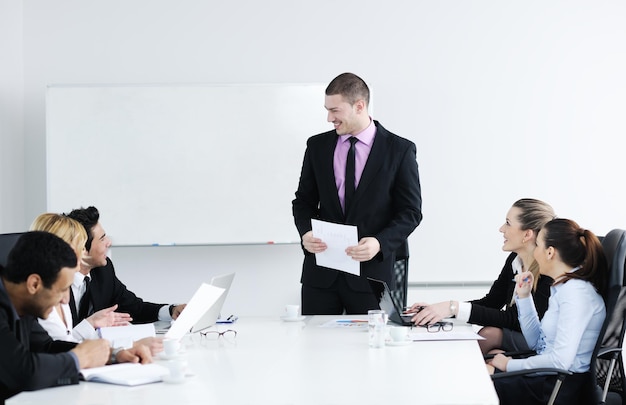 Group of young business people sitting in board room during meeting and discussing with paperwork