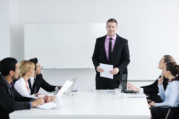 Group of young business people sitting in board room during meeting and discussing with paperwork