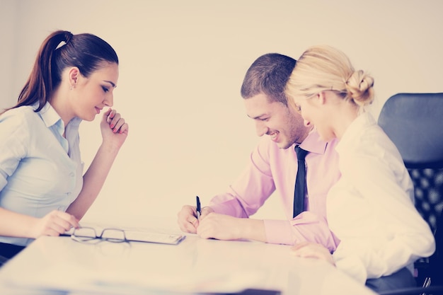 Group of young business people sitting in board room during meeting and discussing with paperwork