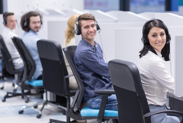 Foto gruppo di giovani uomini d'affari con cuffie che lavorano e danno supporto ai clienti in un ufficio di call center