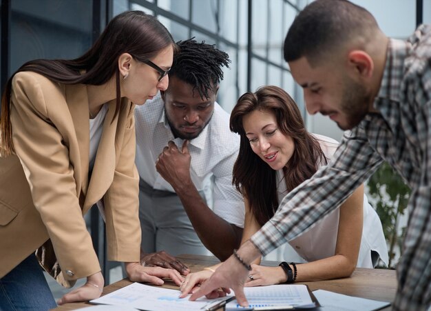 Group of young business people working together while standing in creative office