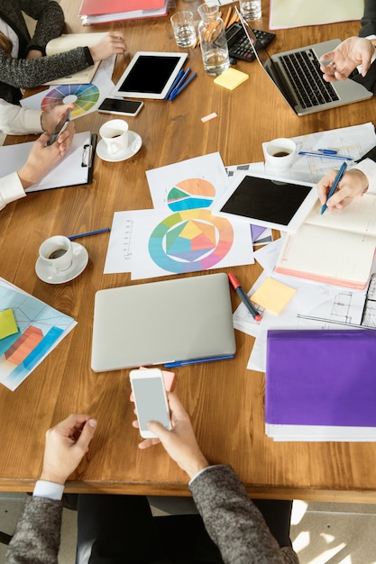 Group of young business professionals having a meeting. Diverse group of coworkers discuss new decisions, future plans, strategy. Creative meeting and workplace, business, finance, teamwork. Top view.