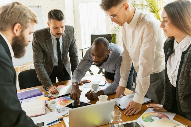 Group of young business professionals having a meeting. Diverse group of coworkers discuss new decisions, future plans and strategy. Creative meeting and workplace, business, finance, teamwork.