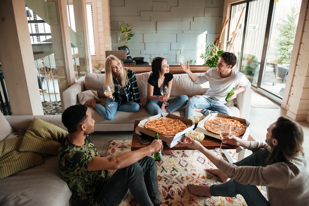 Group of young cheerful friends hanging out together at home