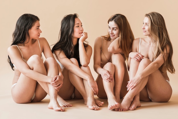 Group of young cheerful women in underwear sitting on floor