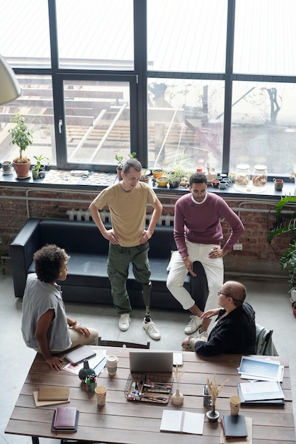 Group of young co-workers in casualwear discussing ideas for new project