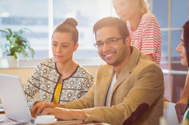 Group of young colleagues using laptop at office