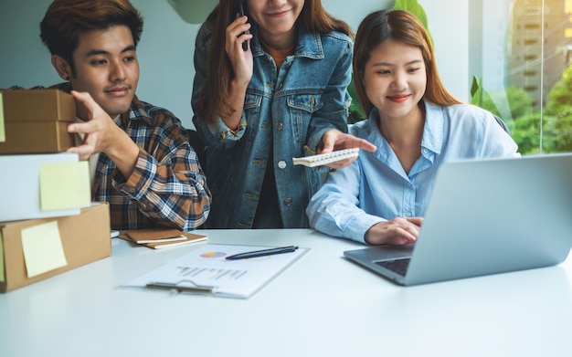 Un gruppo di giovani imprenditori che confermano e controllano gli ordini dei clienti al telefono per lo shopping online e il concetto di consegna