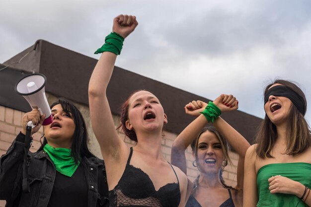 Group of young feminist activists enjoying the protest on road surrounded by green smoke