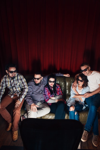 Group of young friends in 3d glasses have fun entertainment watching tv show on couch together, top view