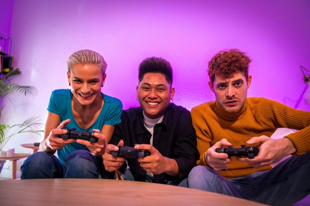 Gruppo di giovani amici che giocano insieme ai videogiochi sul divano a casa ritratto che guarda l'obbiettivo
