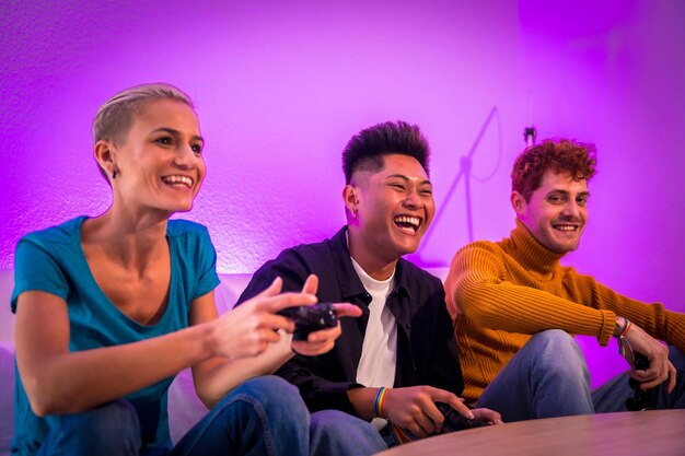 Group of young friends playing video games together on the sofa at home purple led young millennials