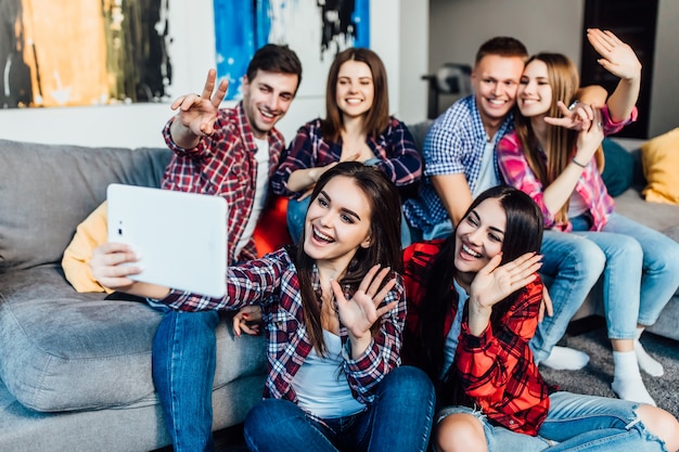 Group of young friends sitting at home on sofa and chated with their parents online