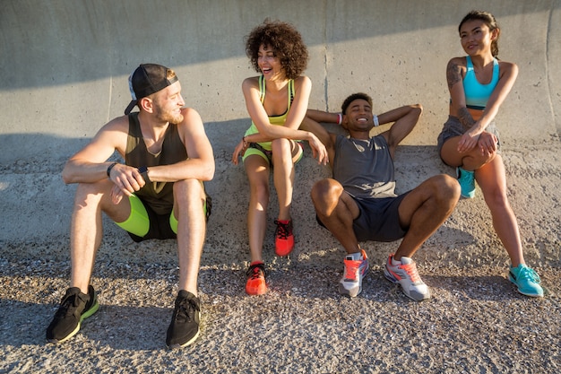 Foto gruppo di giovani amici in abiti sportivi che riposano e che parlano all'aperto