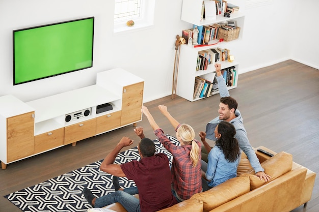 Group Of Young Friends Watching Sports On Television And Cheering