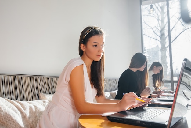 A group of young girls sit in an office and work at computers. Communication and training online.