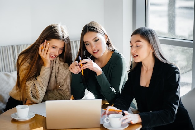 A group of young girls sit in an office and work at computers. Communication and training online.