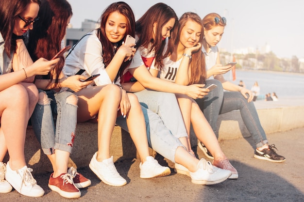 Group of young happy girls real friends students using mobile at city street 