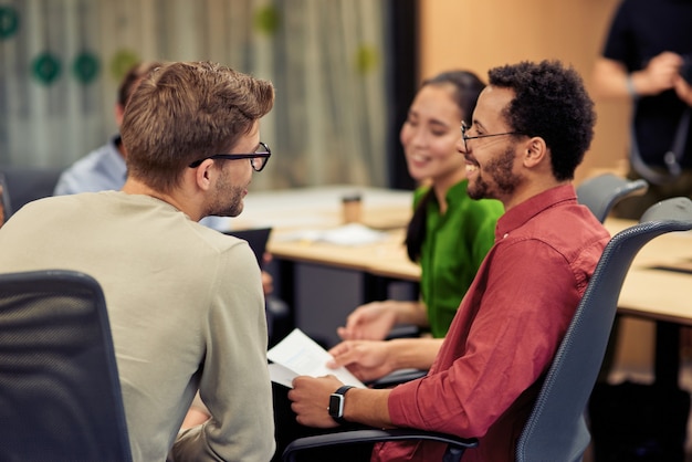 Group of young happy multi racial coworkers communicating and sharing ideas while working together