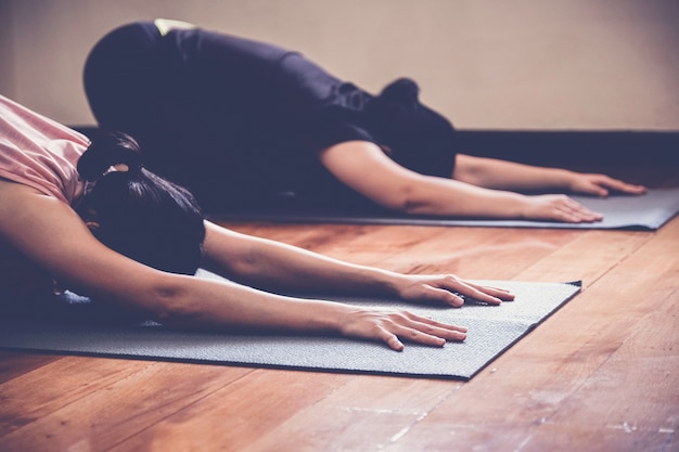 Gruppo di giovani donne asiatiche in buona salute che praticano lezione di yoga, posa del bambino con l'istruttore in studio domestico.