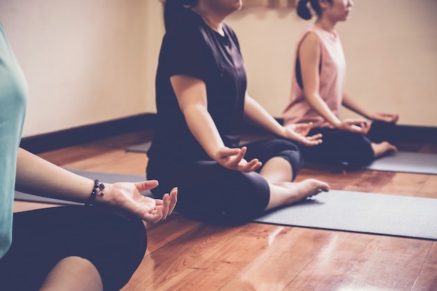 Foto gruppo di giovani donne asiatiche in buona salute che praticano lezione di yoga, posa del loto con l'istruttore in studio domestico.