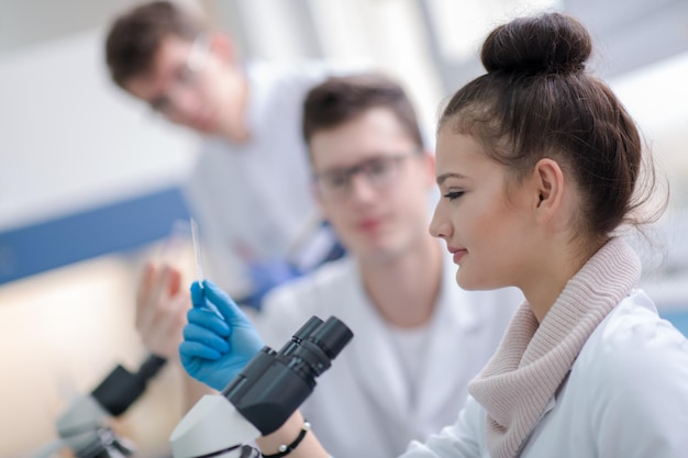 Gruppo di giovani studenti di medicina che fanno ricerca insieme nel laboratorio di chimica, lavoro di squadra di studenti universitari al chiuso