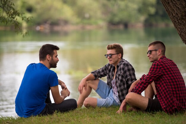 Group of young  men enjoying the nature sitting on the bank of the river