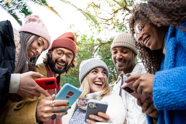 group of young mixed race friends using cell phones outdoors. concept of technology addicted people