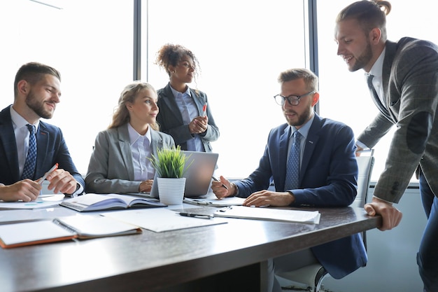 Group of young modern people in formalwear smiling and discussing something while working in the modern office.