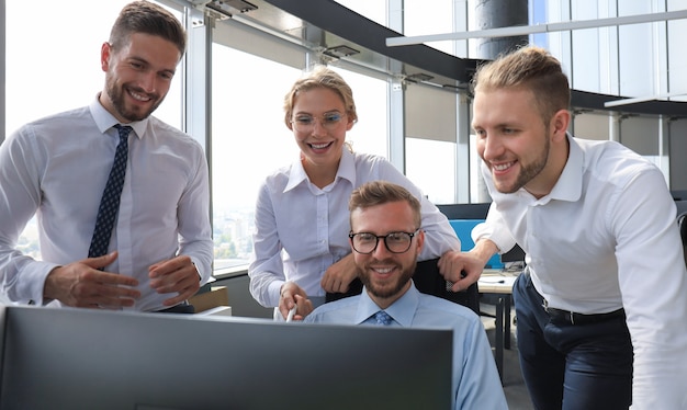 Group of young modern people in formalwear using modern technologies while working in the creative office.