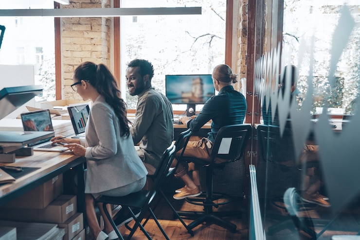 Photo group of young modern people in smart casual wear communicating and using modern technologies while working in the office