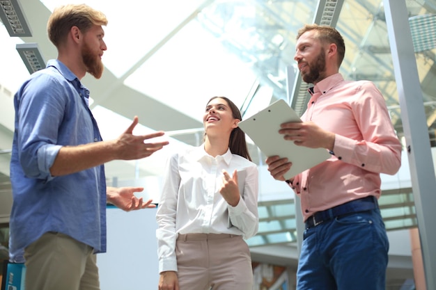 Photo group of young modern people in smart casual wear having a brainstorm meeting while standing in the creative office