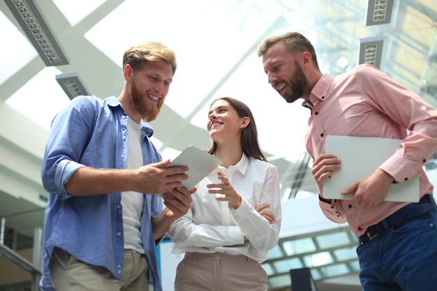 Photo group of young modern people in smart casual wear having a brainstorm meeting while standing in the creative office