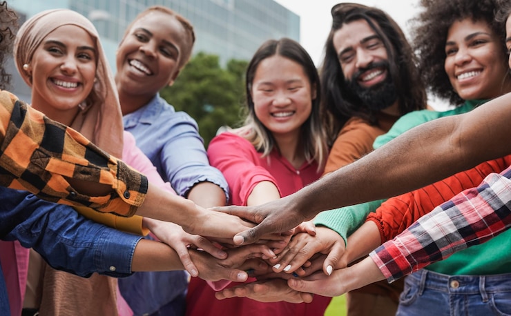 Photo group of young multiethnic people stacking hands in the city