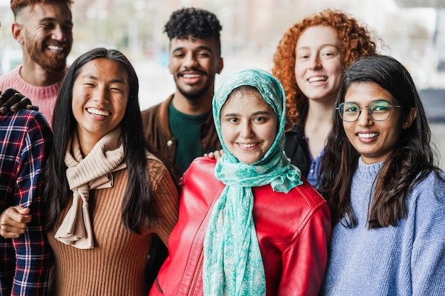 Group of young multiracial friends smiling on camera outdoor Inclusion diversity and friendship concept Main focus on muslim girl face