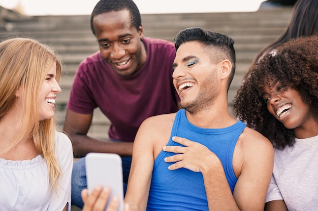 Gruppo di giovani multirazziali che si divertono in città con il telefono cellulare - concetto di diversità e amicizia